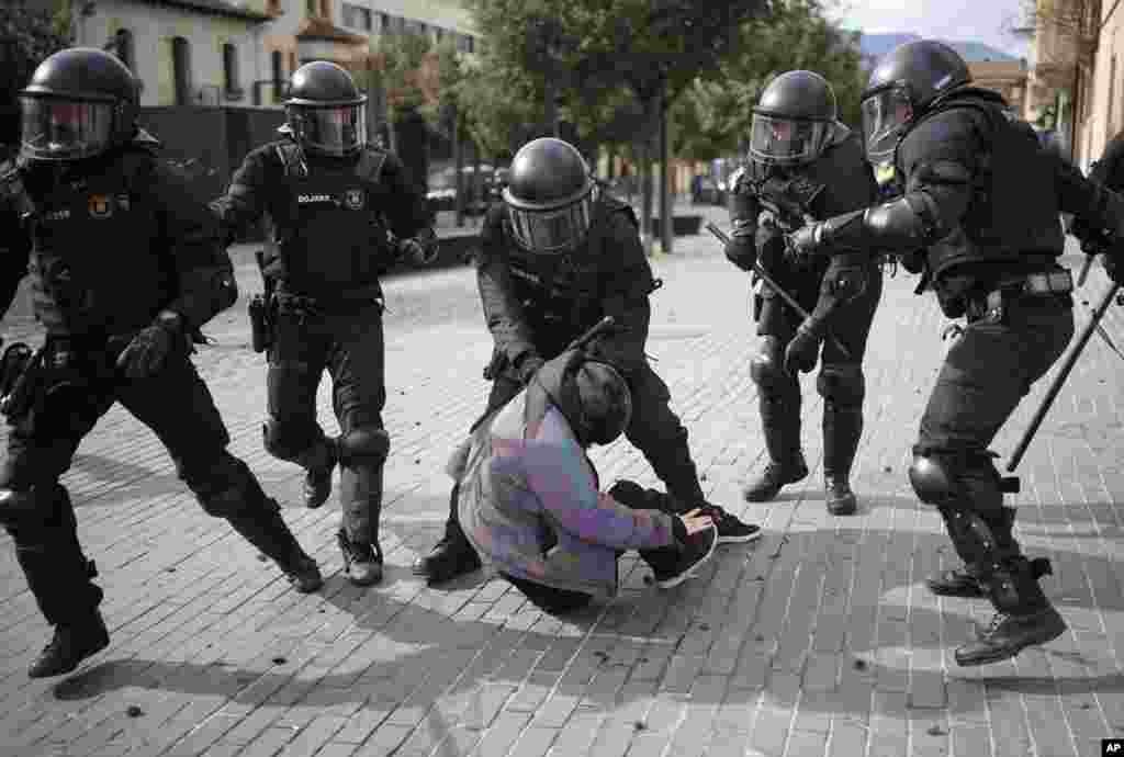 A demonstrator is detained by police officers during a protest against Spain's far-right Vox party supporters in Olot city, in Girona province.