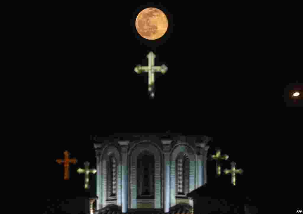 The "snow" moon rises behind the Church of Saint John the Baptist in Skopje, Northern Macedonia, Feb. 27, 2021.
