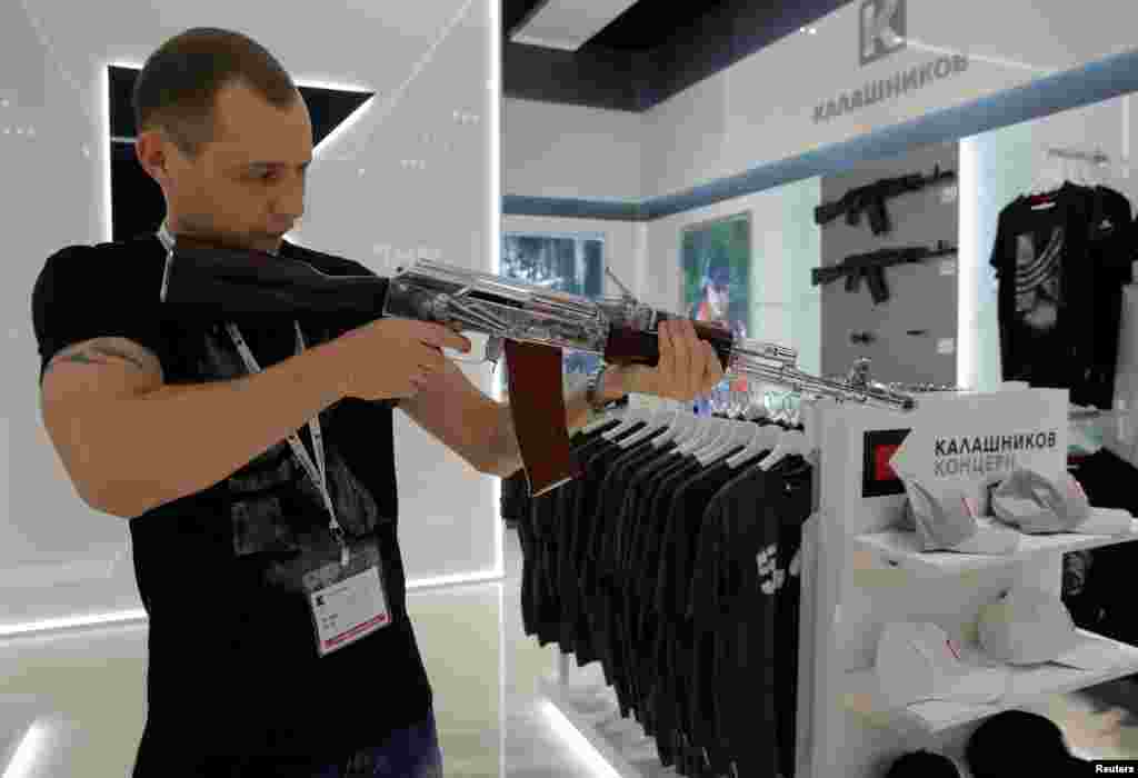 Seorang penjual mendemonstrasikan "model" senjata AK-47 pada toko souvenir senjata Kalashnikov di bandara Sheremetyevo, Rusia.