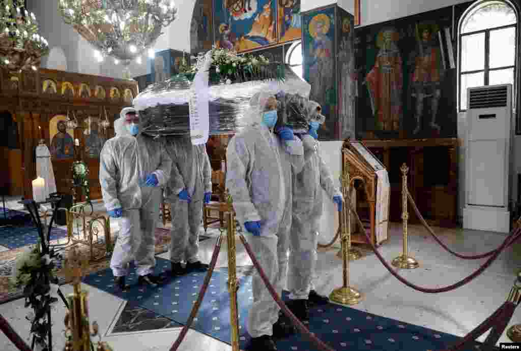 Pallbearers, wearing personal protective equipment (PPE), carry the coffin of a patient who died from the COVID-19, inside a church in Athens, Greece.