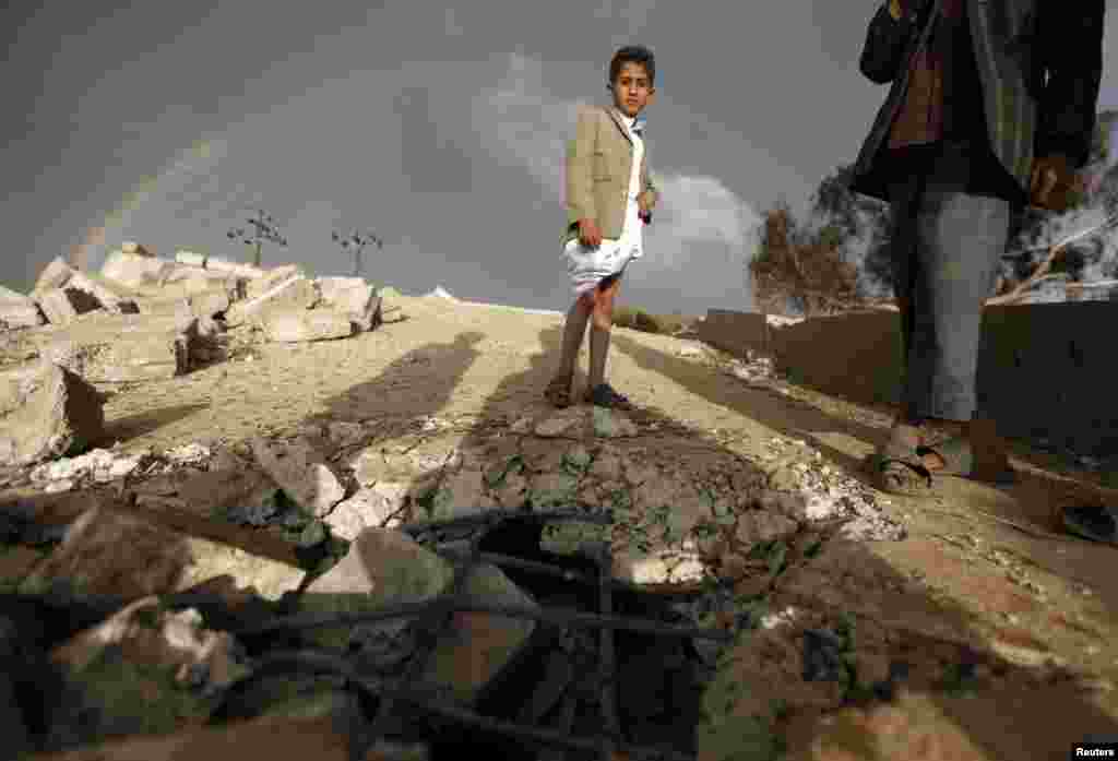 A boy stands on the ruins of his school which was bombed by militants of the Shi'ite al-Houthi group during recent conflicts against local tribes in the Hamdan area west of the Yemeni capital Sanaa, March 23, 2014.