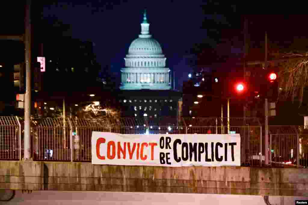 A banner reading, "Convict or be complicit" is hung over a bridge on the first day of the Senate impeachment trial against former President Donald Trump in Washington, D.C., Feb. 9, 2021.