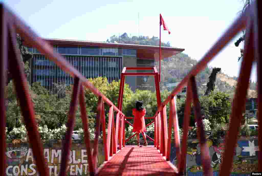 A woman stands at an urban intervention by Chilean artist Ivan Navarro called "Rio de sangre" (Blood river), a tribute to the coronavirus victims and in memory of the people thrown into the river during the Chilean dictatorship, in Santiago, Chile.