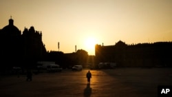 Una mujer camina por el Zócalo de la Ciudad de México, la madrugada del jueves 30 de mayo de 2024. Los votantes mexicanos acudirán a las urnas el 2 de junio para elegir un nuevo presidente.