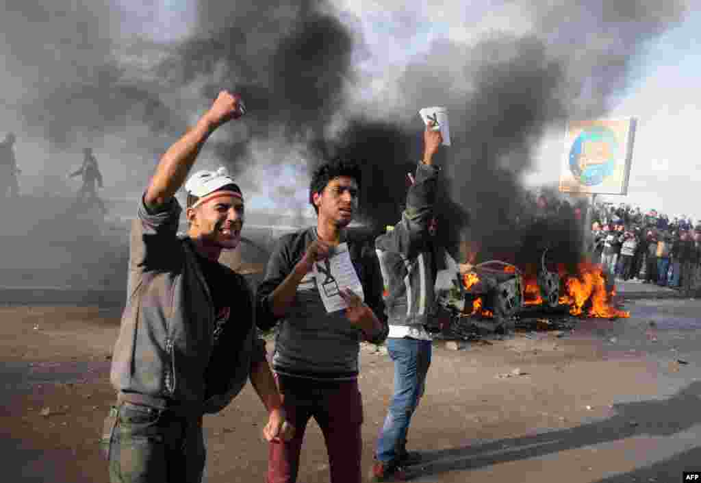 Egyptian protesters shout slogans in front of burning cars set on fire during a demonstration calling for a "No" vote in a referendum on a new constitution in the coastal city of Alexandria, Dec. 14, 2012.