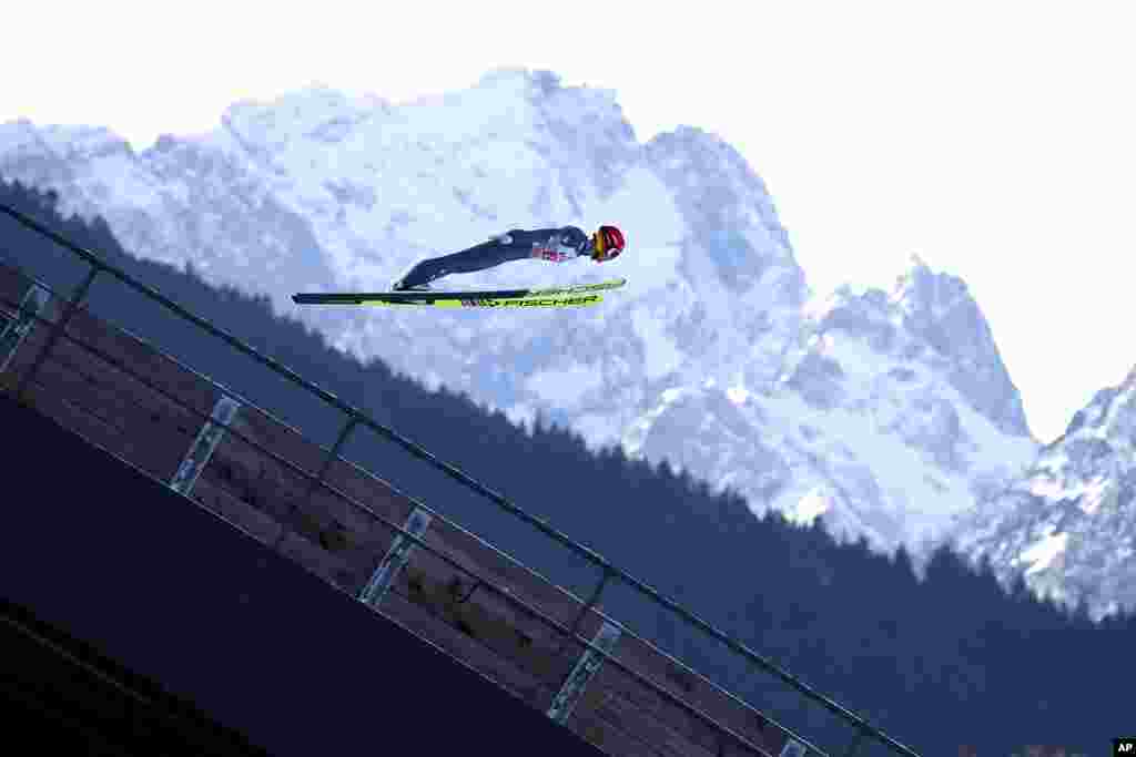 Philipp Aschenwald of Austria soars through the air, with Germany's highest mountain, the Zugspitze, in the background, during a trial jump at the second stage of the 69th Four Hills ski jumping tournament in Garmisch-Partenkirchen, Germany.