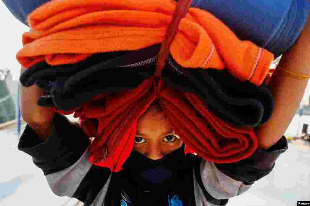 A Rohingya girl carries blankets as she prepares to board a ship to move to Bhasan Char island near Chattogram, Bangladesh.