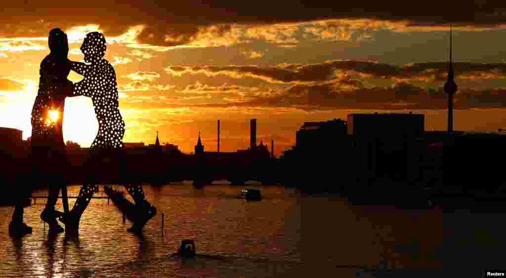 Matahari terbenam di belakang patung "Molecule Men", setinggi 30 meter karya Jonathan Borofsky, di Berlin, Jerman.