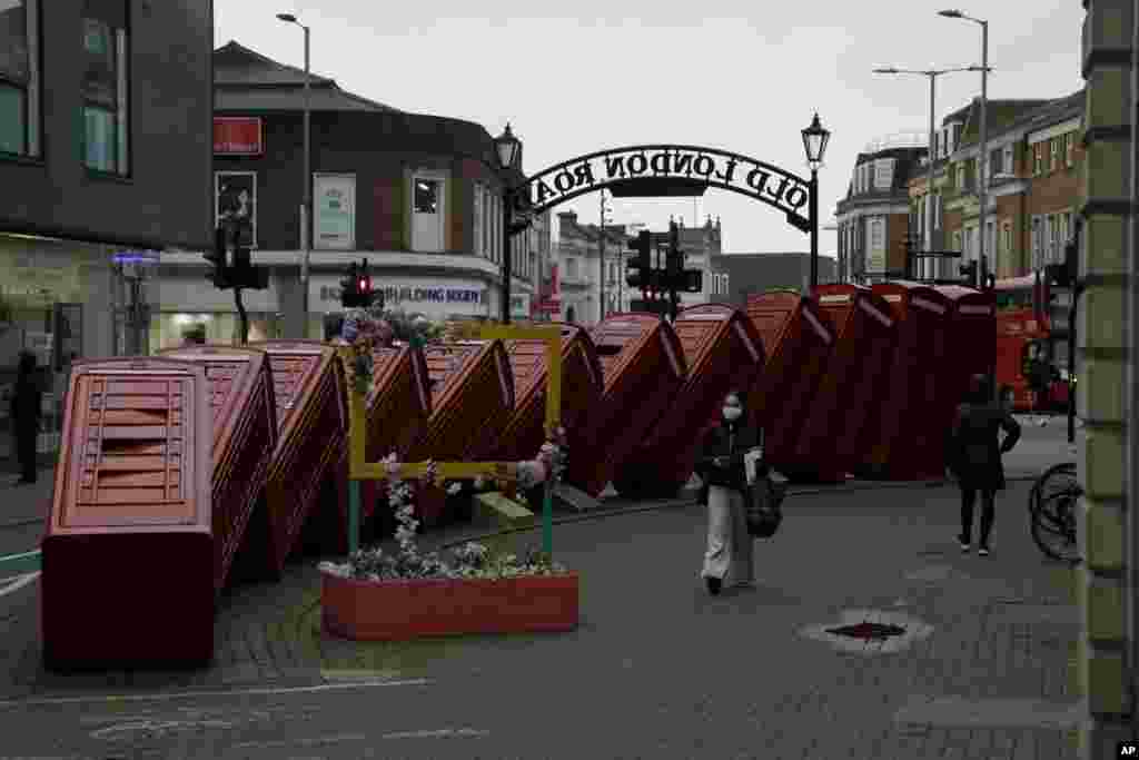 A woman walks past "Out of Order" a 1989 red phone box sculpture by British artist David Mach, in Kingston upon Thames, south west, London, during England's third national lockdown since the coronavirus outbreak began.