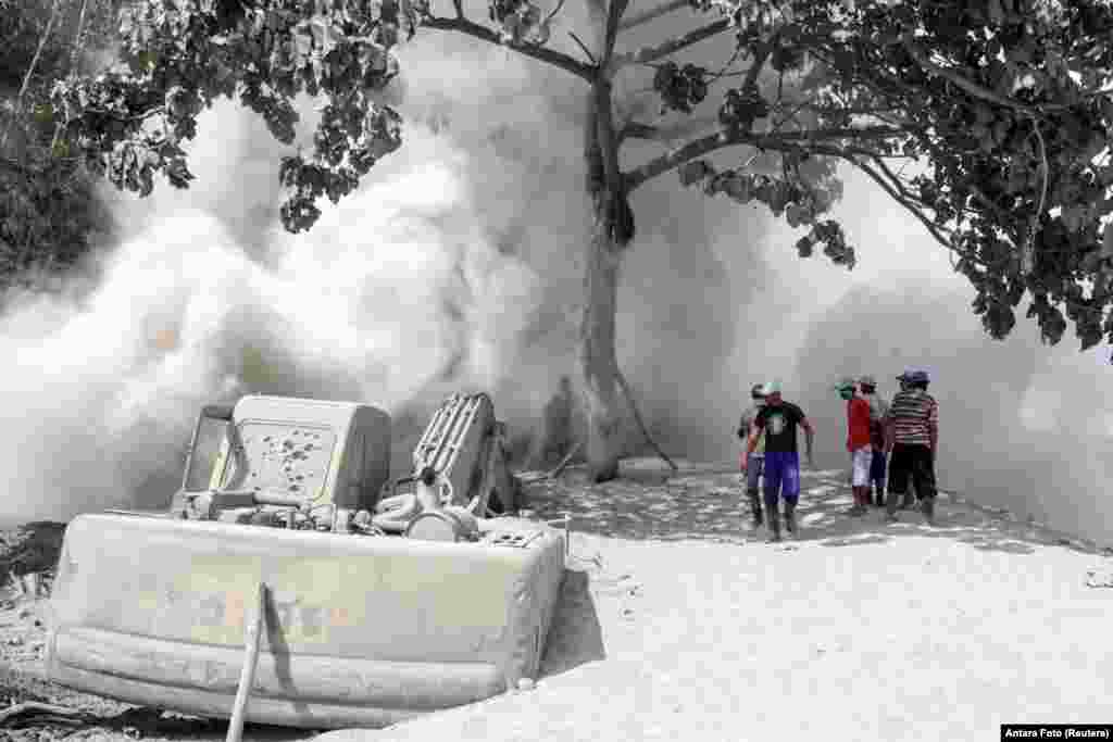 People are seen on a road blanketed with volcanic ash from the erupting Mount Semeru in Lumajang, East Java Province, Indonesia.