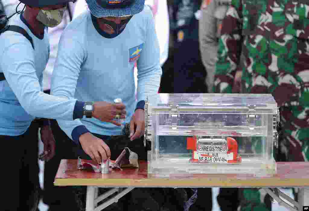 Indonesian Navy personnel handle a box containing the flight data recorder recovered from the crash site of the Sriwijaya Air flight SJ-182 in the Java Sea at Tanjung Priok Port.