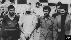 FILE - One of 60 U.S. hostages, blindfolded and with his hands bound, is being displayed to the crowd outside the U.S. Embassy in Tehran by Iranian hostage takers, Nov. 9, 1979. 