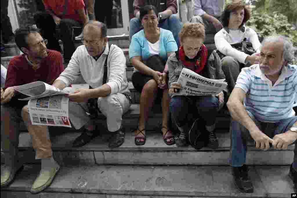 Protesters read newspapers outside Greek state television ERT headquarters during general strike in Athens, June 13, 2013.