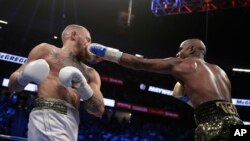 FILE - Floyd Mayweather Jr. jabs Conor McGregor in a super welterweight boxing match, in Las Vegas, Aug. 26, 2017.