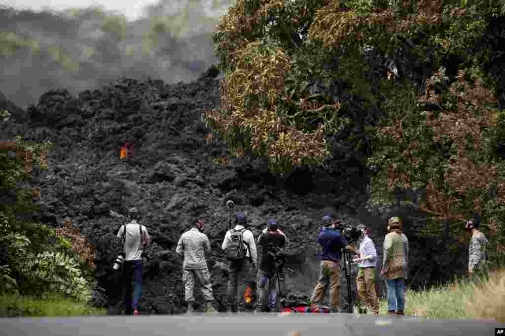 Members of the media record a wall of lava entering the ocean near Pahoa, Hawaii, May 20, 2018. Kilauea volcano, oozing, spewing and exploding on Hawaii's Big Island, has gotten more hazardous in recent days, with rivers of molten rock pouring into the ocean and flying lava causing the first major injury.