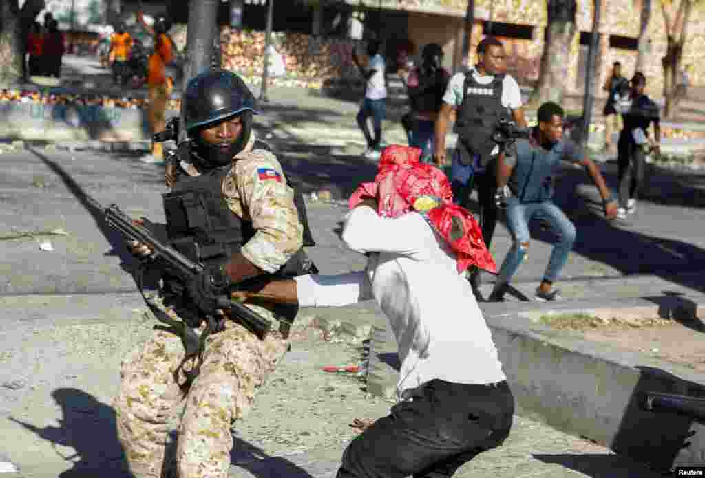 A demonstrator tries to grab the rifle of a police officer during protests against Haiti's President Jovenel Moise, in Port-au-Prince, Feb. 8, 2021.