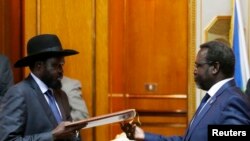 FILE - South Sudan's President Salva Kiir (L) and the country's rebel leader, Riek Machar, exchange signed peace agreement documents in Addis Ababa May 9, 2014.
