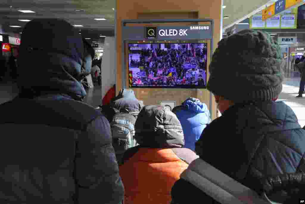People watch a TV screen showing the news on a violent mob that loyal to U.S. President Donald Trump stormed the U.S. Capitol, at the Seoul Railway Station in Seoul, South Korea.