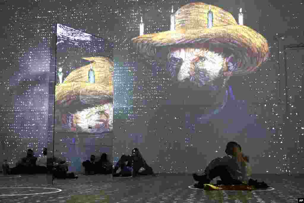 Patrons look at images cast on the wall and reflected in a mirror during a virtual display titled "Immersive Van Gogh" at the Lighthouse ArtSpace, in Chicago, Feb. 18, 2021.
