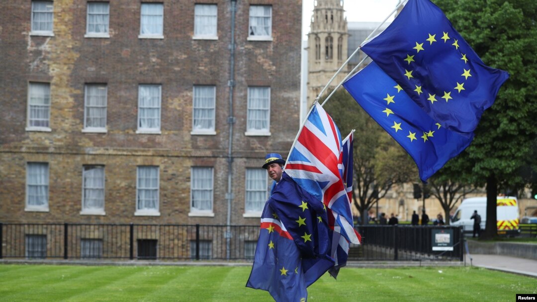 An anti-Brexit protester carries flags opposite the Houses of Parliament in London, Britain, May 10, 2018. Britain's ruling party is divided over how it wants to withdraw from the European Union.