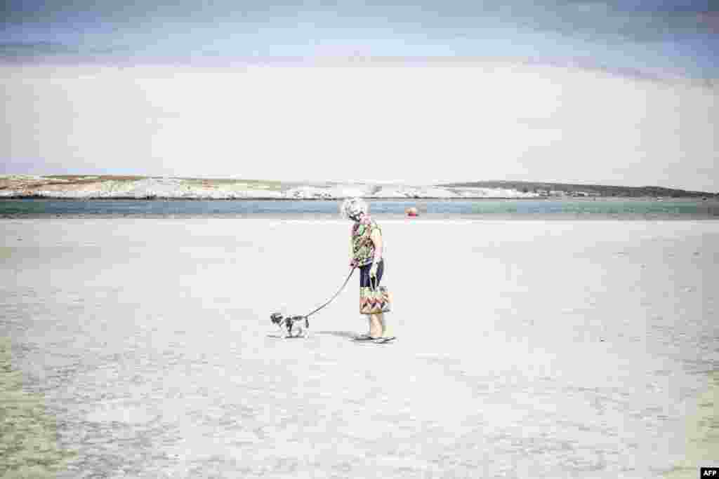An elderly woman walks her dog in the empty Main Beach in Langebaan, South Africa. President Cyril Ramaphosa announced new lockdown measures to limit the spread of COVID-19. 