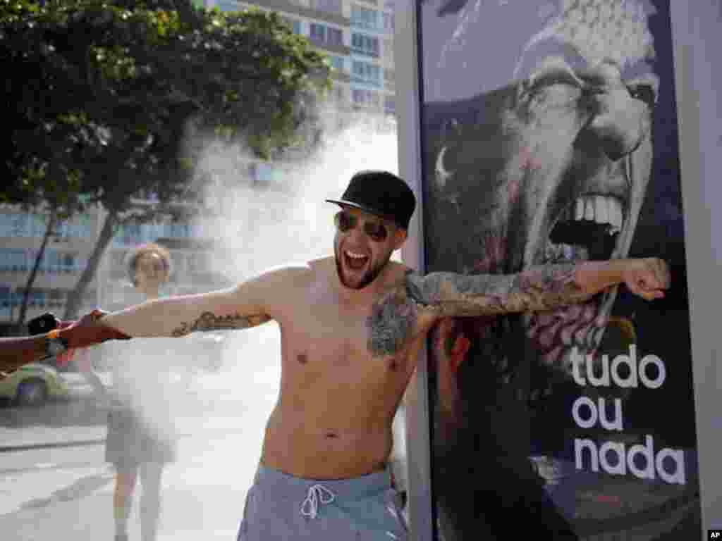Um jovem simula uma dentada de Suárez no seu braço, encostando-se ao muppi de publicidade exposto na praia de Copacabana. Junho 2014