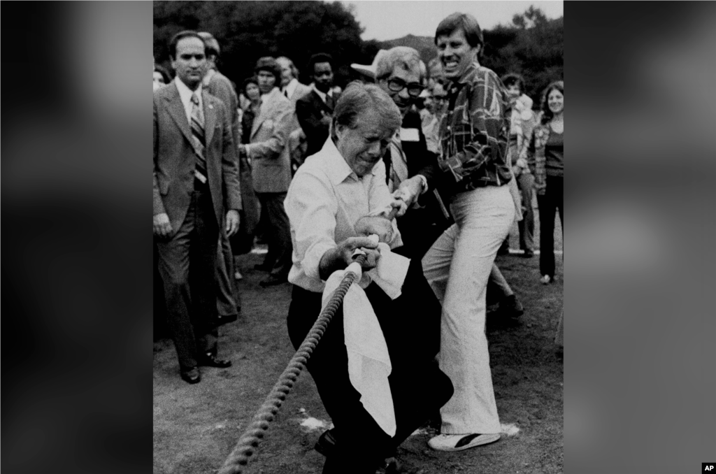 26 сентября 1976 года. Картер принимает участие в перетягивании каната на предвыборном митинге в Калифорнии. Спустя месяц ему в итоге удалось «перетянуть» на себя голоса большей части американцев: в ходе голосования в ноябре стало известно, что за Картера проголосовали 50,1% избирателей (и 297 голосов выборщиков). По итогам голосования, Форд завоевал 240 голосов выборщиков.