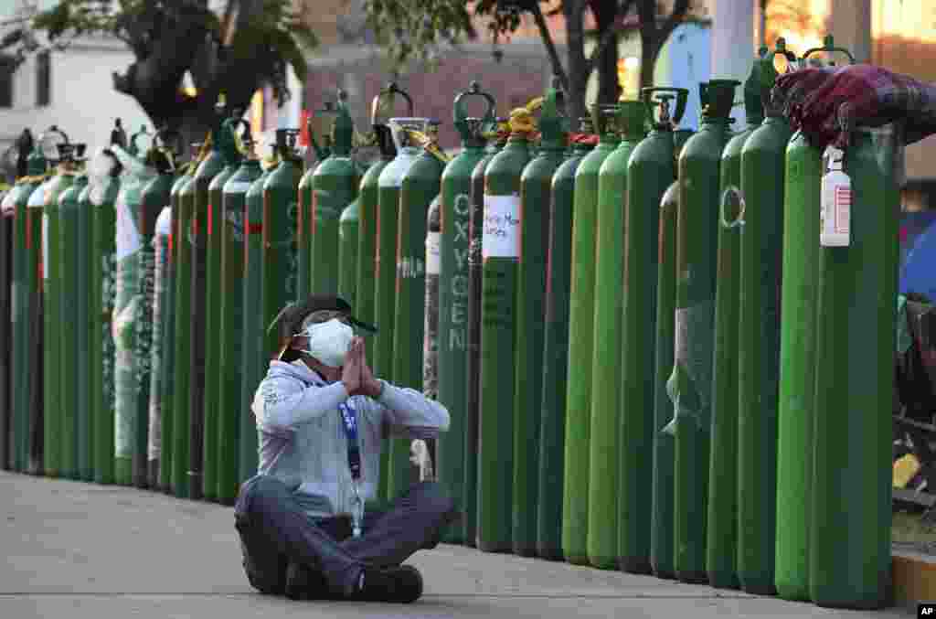 Alejandro Ccasa prays for his uncle who has COVID-19 after waiting three days outside a oxygen refill shop before it opens in Callao, Peru.