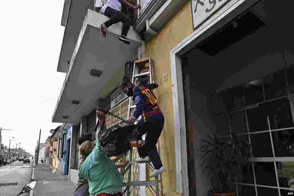 A teenager is helped with a ladder as she climbs down from a building to escape the Zafiro I shelter in Guatemala City, Feb. 17, 2021.
