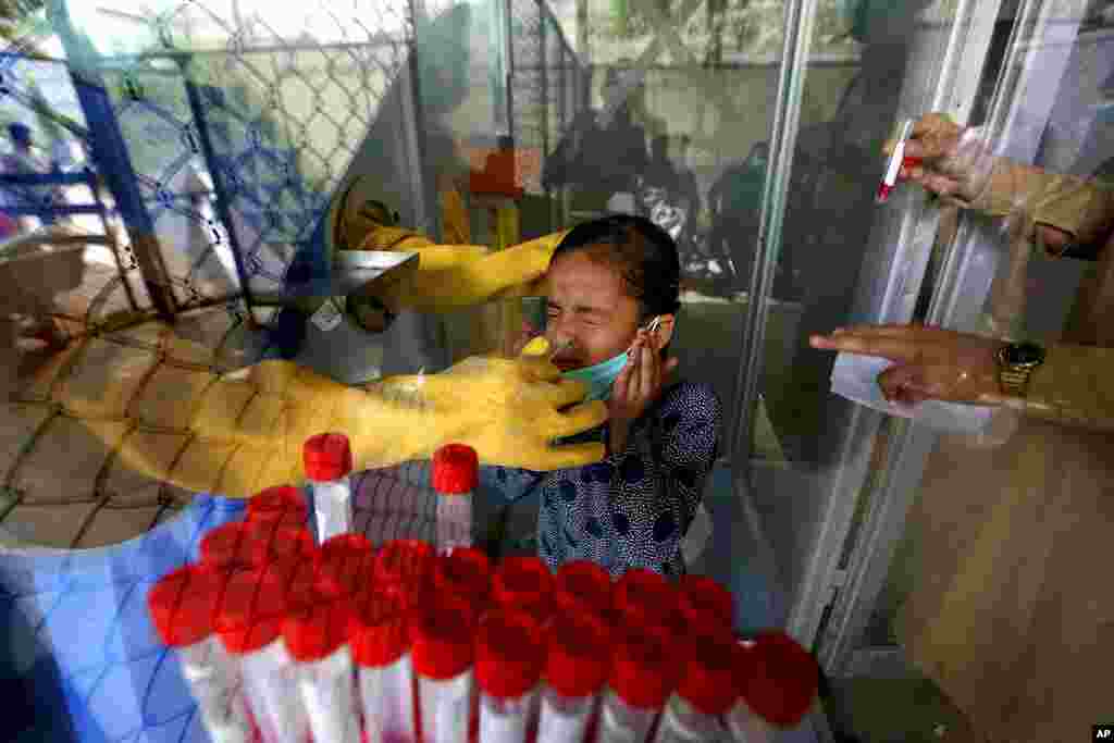 A young girl reacts while having a nasal swab sample taken by a health worker at a COVID-19 testing facility in a hospital in Karachi, Pakistan.