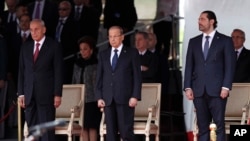 Lebanese President Michel Aoun, center, Lebanese Prime Minister Saad Hariri, right, and Lebanese Parliament Speaker Nabih Berri, left, attend a military parade to mark the 74th anniversary of Lebanon's independence from France in downtown Beirut, Nov. 22, 2017.