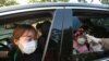 A young girl has her temperature checked as she arrives to watch a drive-in concert at the Gyeongbok Palace parking lot in Seoul, South Korea, July 17, 2020. 