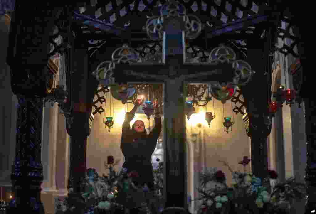 An Orthodox Church believer lights candles before the liturgy on Orthodox Christmas Eve in the Prechistensky, the Cathedral Palace in Vilnius, Lithuania.