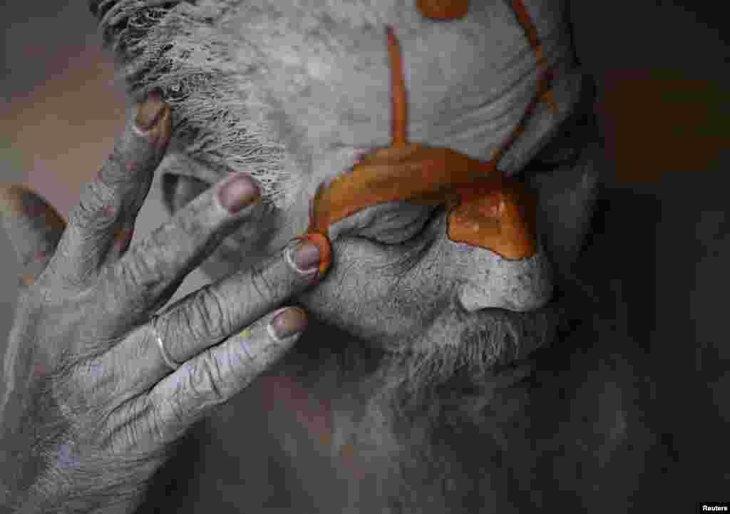 Orang Hindu sadhu (orang suci) mengecat dahinya di Kuil Pashupatinath di Kathmandu, Nepal. Orang-orang suci Hindu dari Nepal dan India datang ke kuil tersebut sebagai bagian dari festival Shivaratri, yang jatuh pada 10 Maret. (Reuters/Navesh Chitrakar) 
