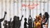 People walk past graffiti reading in Arabic "Freedom, Peace, Justice and Civilian" in the Burri district of Khartoum, Khartoum, Sudan.