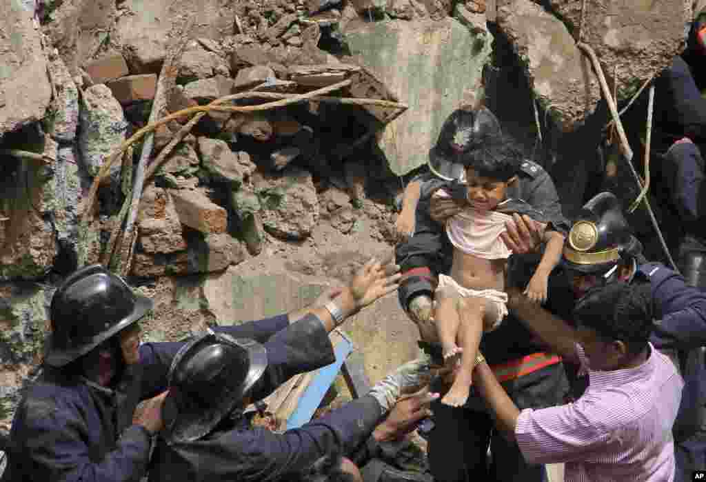 Fire officials rescue a girl from debris of a collapsed building in Mumbai, Sept. 27, 2013.