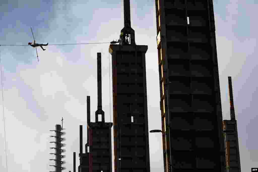 Italian funambulist Andrea Loreni performs on a steel rope at 25 meters high between two towers of a disused factory in Parco Dora in Turin, Italy.