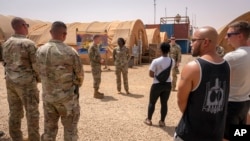 Nesta imagem da Força Aérea dos EUA, o major-general Kenneth P. Ekman fala com militares em frente a um cartaz "Bem-vindo a Niamey" que representa veículos militares dos EUA na Base Aérea 101 no Níger, a 30 de maio de 2024 (arquivo)
