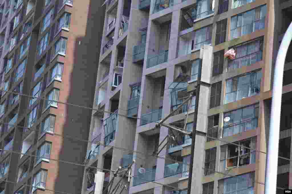 天津爆炸事故現場,核心爆炸區週圍多座居民樓窗戶被震碎,高速公路橋樑受損,多輛大貨車被炸翻,小汽車起火或被砸,多名當地居民仍逗留在事故現場。(美國之音記者東方拍攝)
