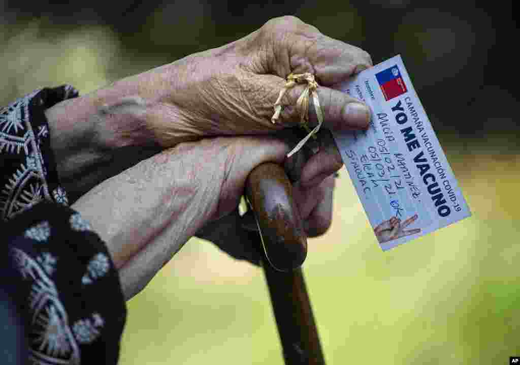 Alicia Martinez holds her vaccination card while resting after her second shot of China's Sinovac COVID-19 vaccine in the outdoor patio of a home for the elderly in Santiago, Chile.hile