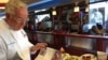 Chev Ype Von Hengst looks over a menu. (Julia Taboh / VOA)