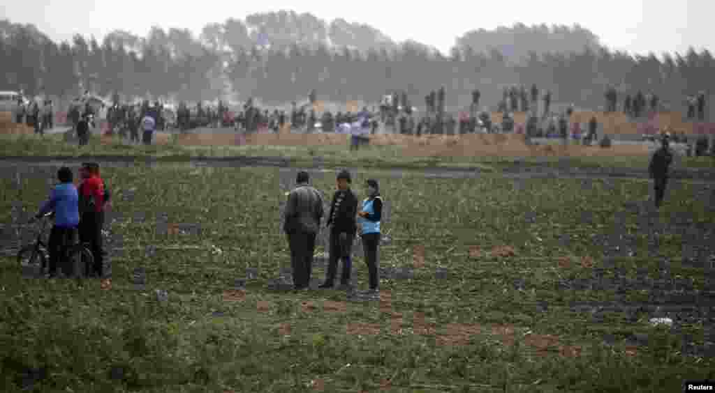 Villagers stand near site of a poultry slaughterhouse fire in Dehui, Jilin province, China, June 3, 2013.