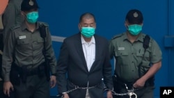 Jimmy Lai, center, who founded the Apple Daily tabloid, is escorted by Correctional Services officers to get on a prison van before appearing in a court, in Hong Kong, Dec. 12, 2020.