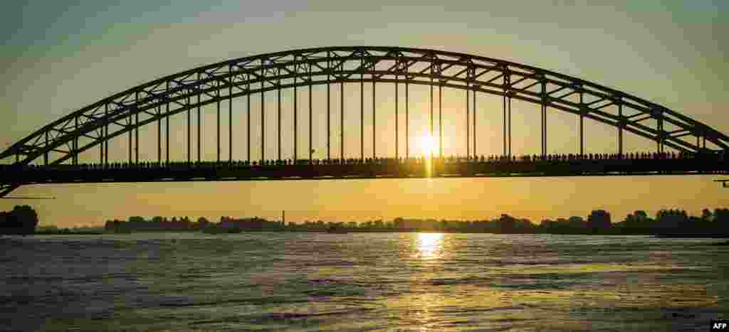 Para peserta melewati jembatan sungai Waal pada hari pertama peringatan tahunan 4 hari 'reli Nijmegen' yang ke-100 tahun di Belanda.
