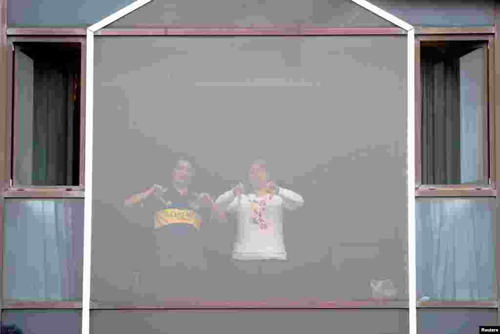 People gesture from a window at the Radisson Blu Hotel at Heathrow Airport, as Britain introduces a hotel quarantine program for arrivals from a "red list" of 30 countries due to the coronavirus pandemic, in London, Britain.