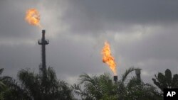 FILE - Gas flares belonging to the Agip Oil company are seen across farmland in Idu, Niger Delta area of Nigeria, Oct. 8, 2021. 