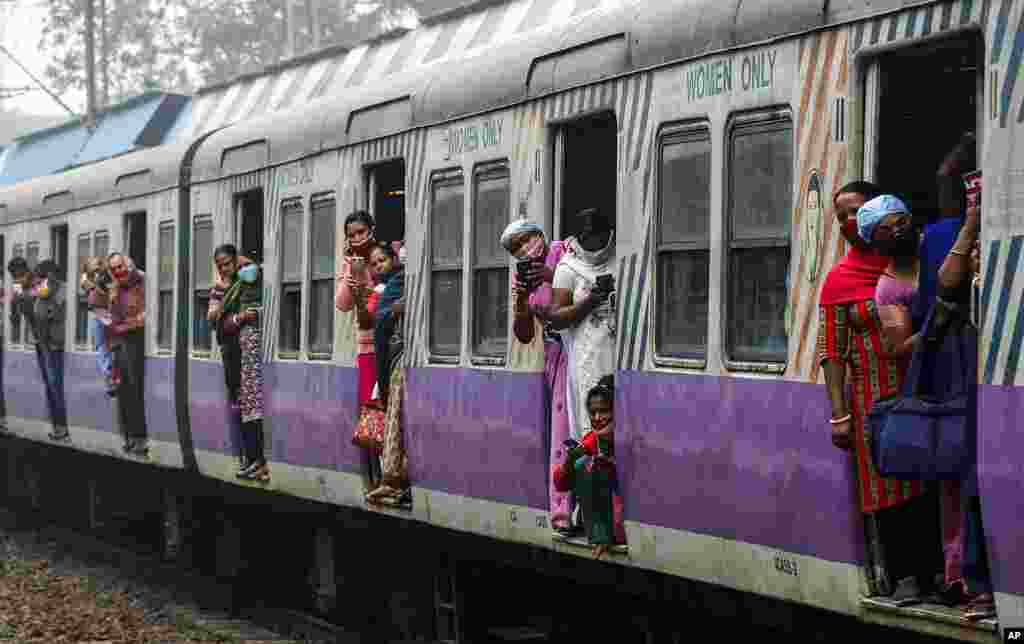 Stranded commuters of a local train look out as supporters of left parties block a train track during a nationwide shutdown called by thousands of Indian farmers protesting new agriculture laws, in Kolkata, India.