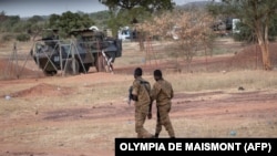 Maafisa wa Jeshi la Burkina Faso wakilinda doria karibu na magari ya kijeshi ya Ufaransa yaliyo egeshwa Kaya, mji mkuu wa Burkina Faso baada ya waandamanaji kuzuia magari hayo yasipite katika eneo hilo yakielekea Niger, Novemba 20, 2021. (Photo by OLYMPIA DE MAISMONT / AFP)