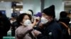 A woman wearing a mask to prevent contracting the coronavirus adjusts her husband's mask as they wait to check in at Incheon International Airport in Incheon, South Korea, March 19, 2020.