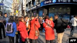 Foreign tourists consult with South Korean tour guides wearing red jackets in a crowded shopping district in Seoul on Apr. 9, 2013.